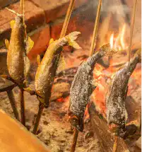 川魚を囲炉裏で焼いている写真